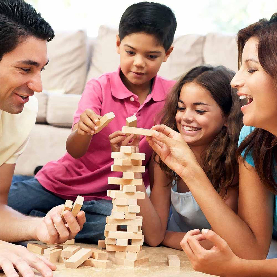 A child cautiously removing a wooden block from the wobbling tower
