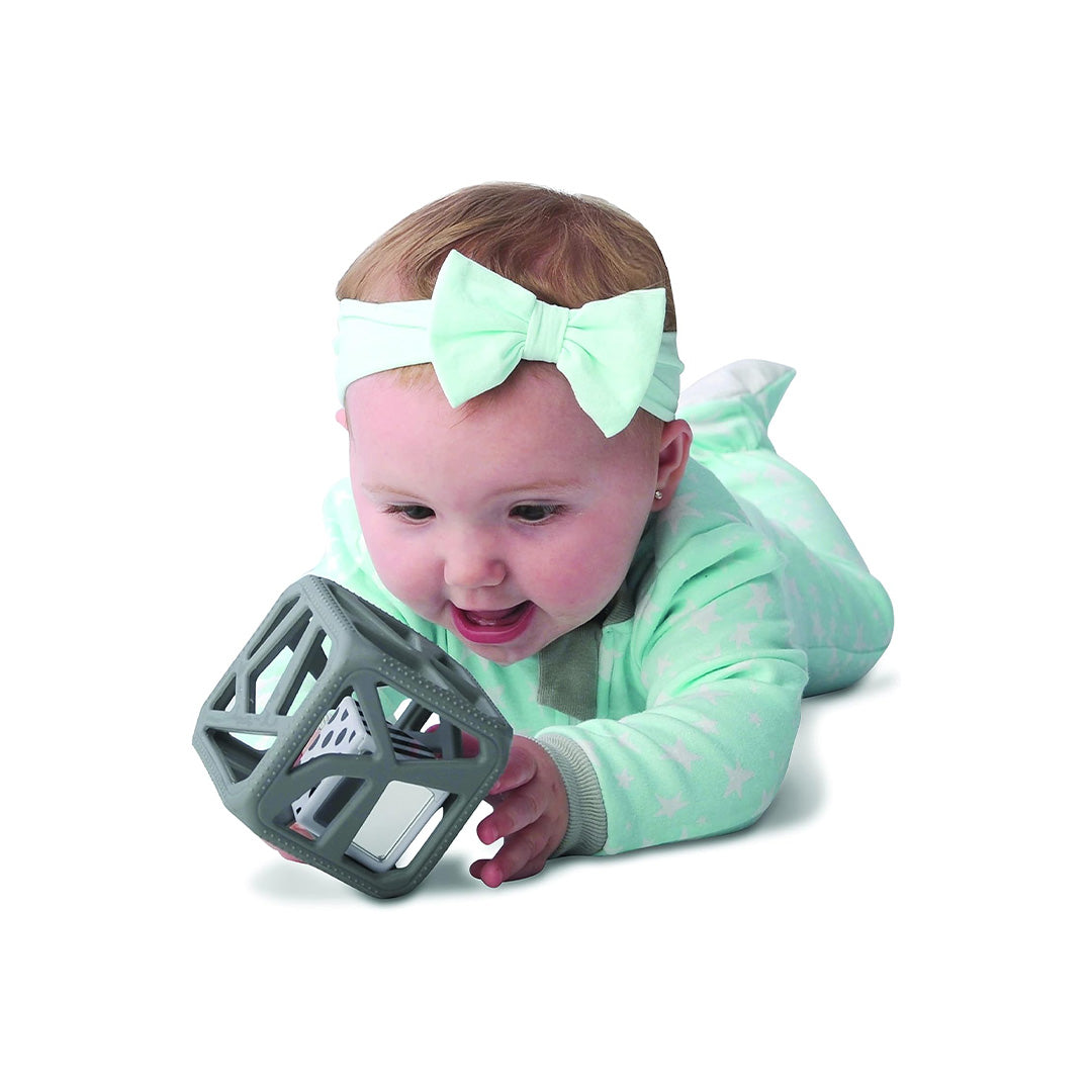 Baby playing with non-toxic toys rattle on a baby play mat.
